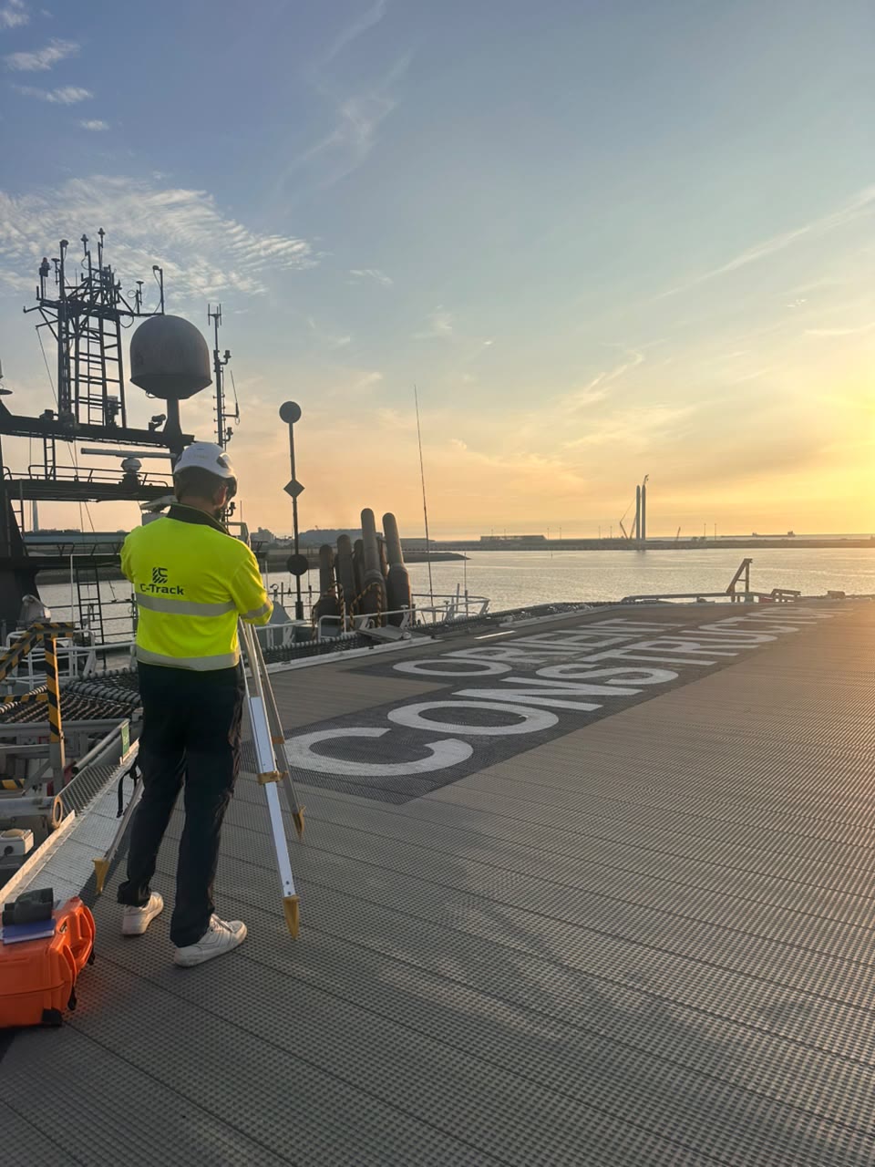 C-TRACK surveyor setting up a survey instrument on a vessel deck at sunrise